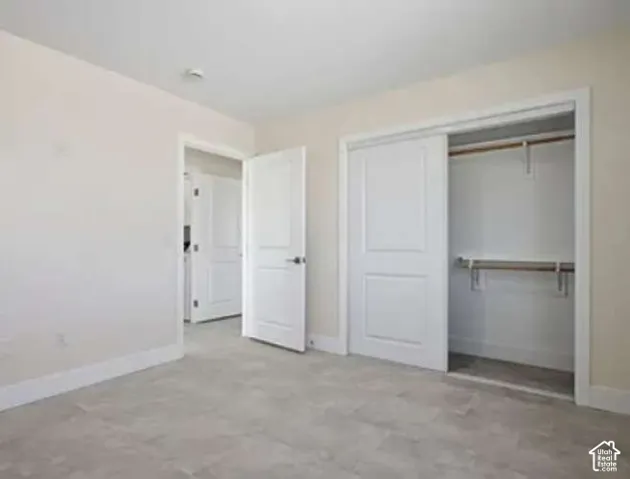 Light-toned walls with contrasting white trim and doors, gray tile flooring, and a built-in closet featuring sliding panel doors and interior shelving