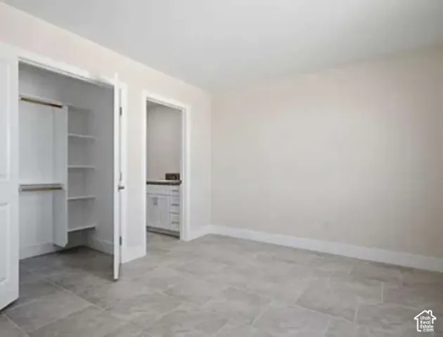 Light-toned wall paint, gray tile flooring, and integrated closet shelving