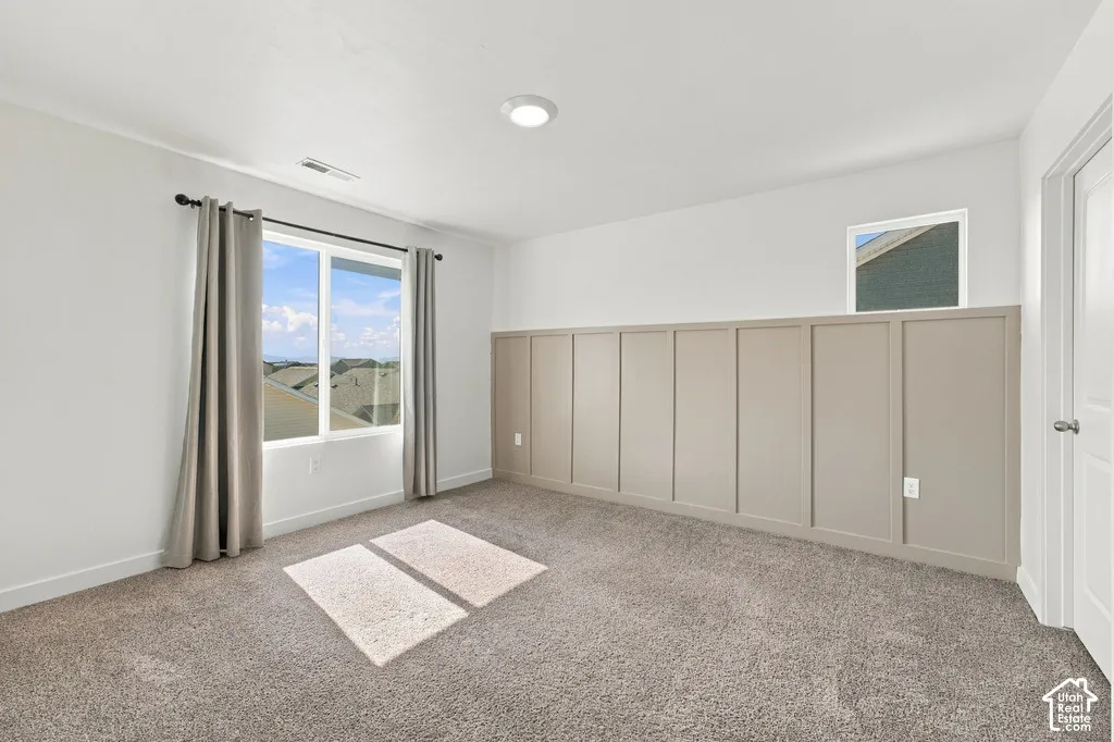Recessed lighting, board and batten accent wall, neutral carpeting, and a white paneled door