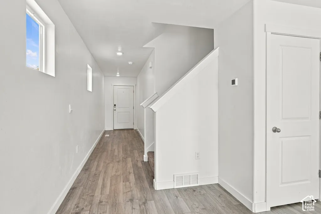 Wood-finish flooring, recessed lighting, white walls, and a multi-panel door