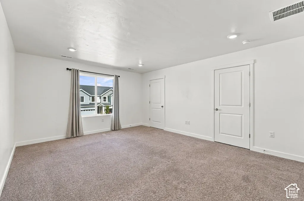 Spacious room featuring neutral carpet, recessed lighting, and a large window with white trim