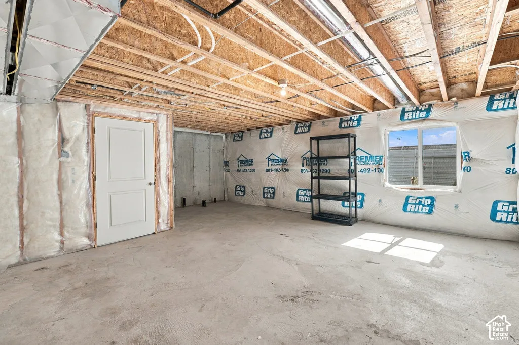 Unfinished lower level with exposed ceiling joists, concrete flooring, and a single window