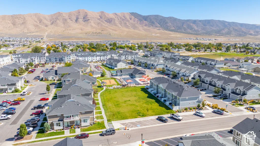 Community featuring multiple residential structures, a central green space, a swimming pool, and dedicated parking areas, all set against a mountain backdrop