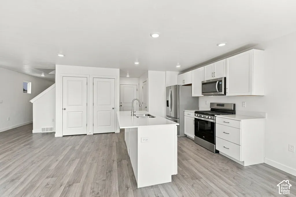 Open-concept kitchen with white cabinetry, stainless steel appliances, and a central island