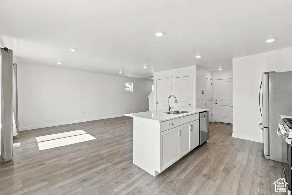 Open-concept living area featuring wood-finish flooring, recessed lighting, and a kitchen island with a built-in sink
