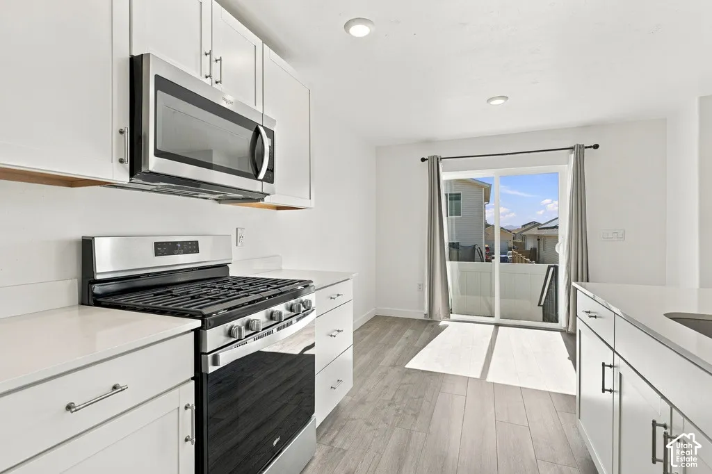 White cabinetry with stainless steel appliances and solid surface countertops