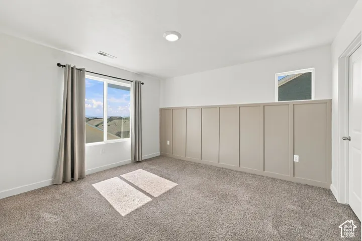 Recessed lighting, board and batten accent wall, neutral carpeting, and a white paneled door