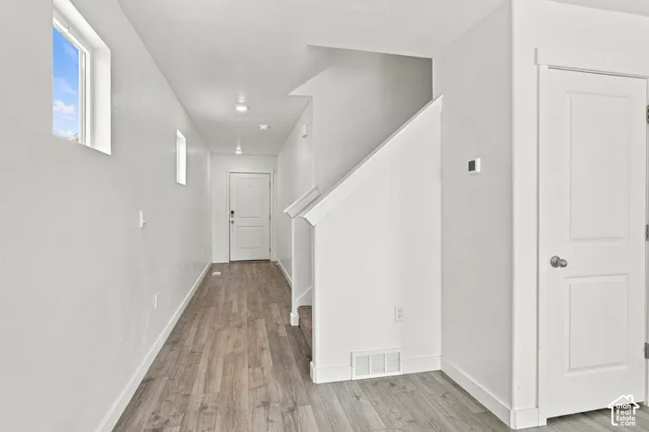Wood-finish flooring, recessed lighting, white walls, and a multi-panel door