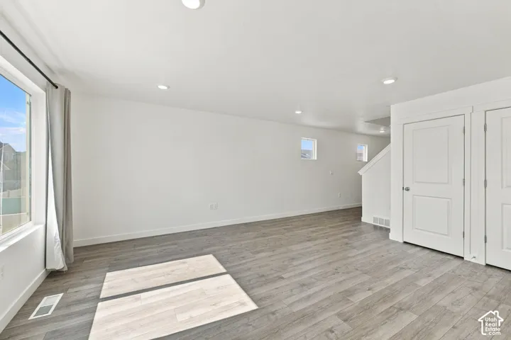 Recessed ceiling lighting, wood-finish flooring, white paneled doors, white walls, and a staircase