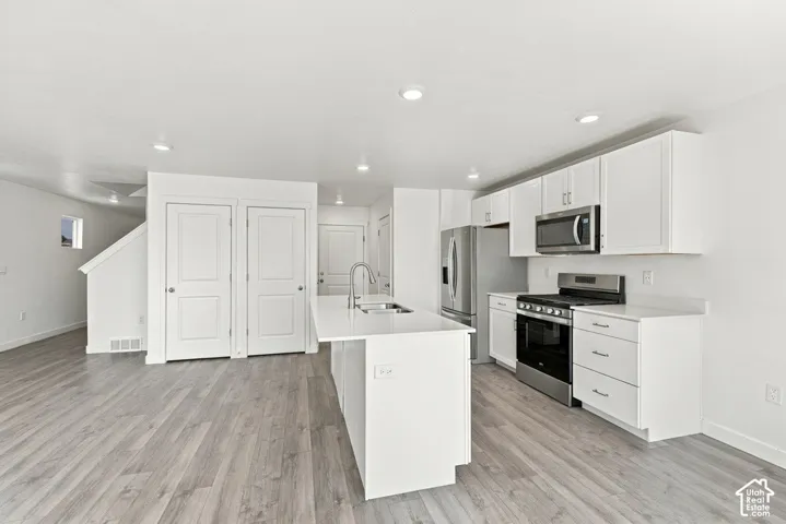 Open-concept kitchen with white cabinetry, stainless steel appliances, and a central island