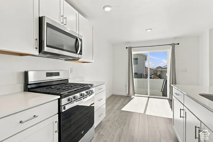 White cabinetry with stainless steel appliances and solid surface countertops