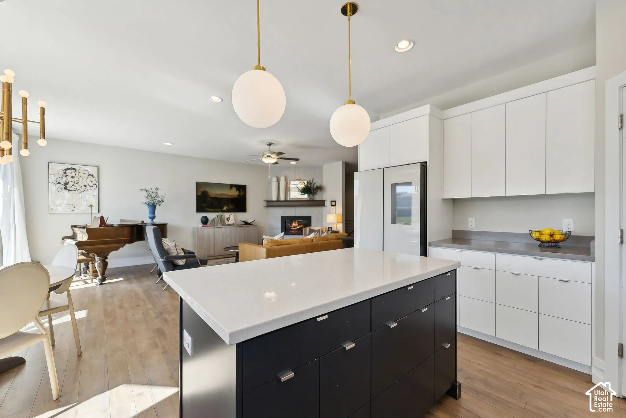 Kitchen island with a light-toned countertop, white cabinetry with dark hardware, and wood-finish flooring