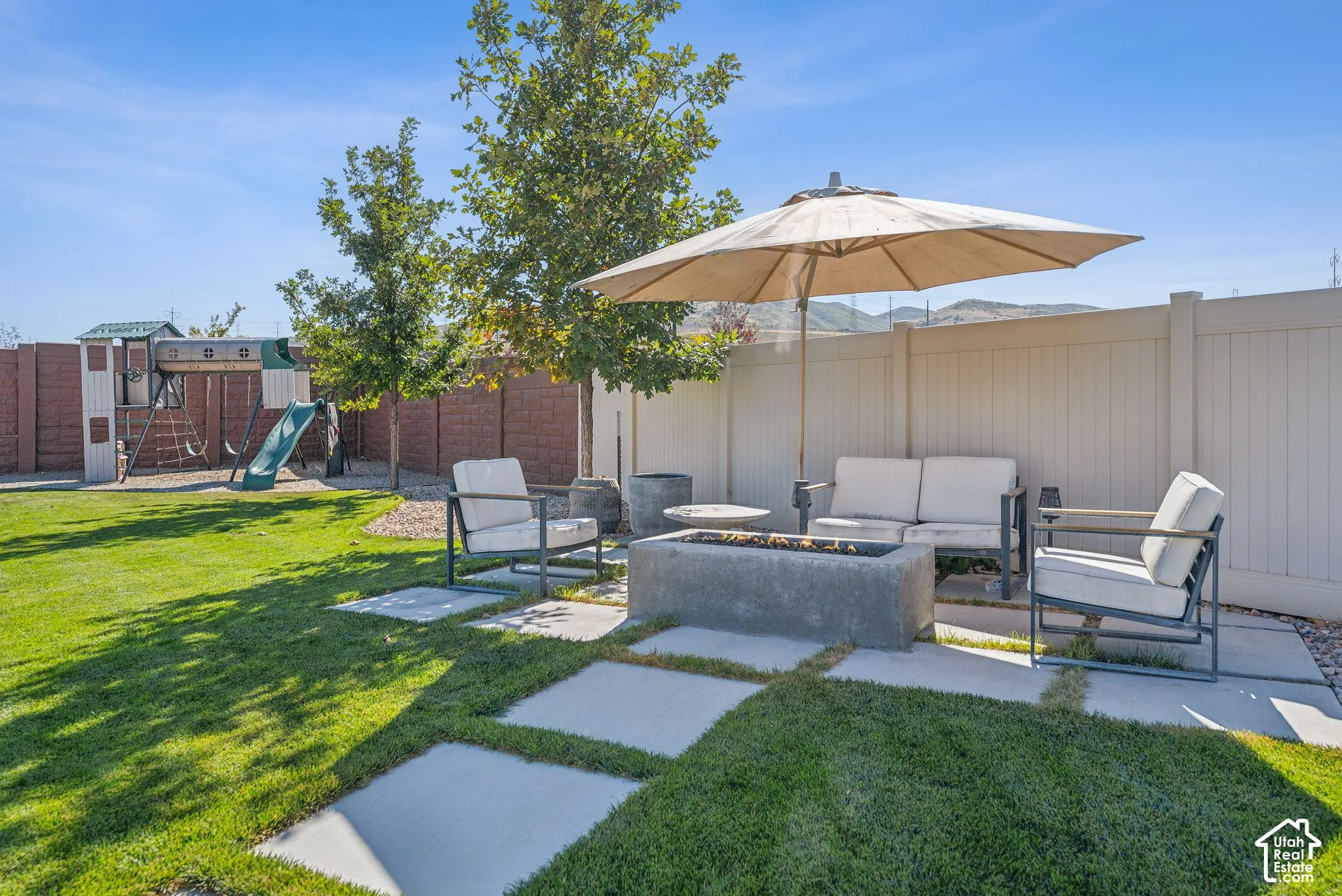 Expansive backyard featuring a concrete fire pit, a paved patio area, and a privacy fence