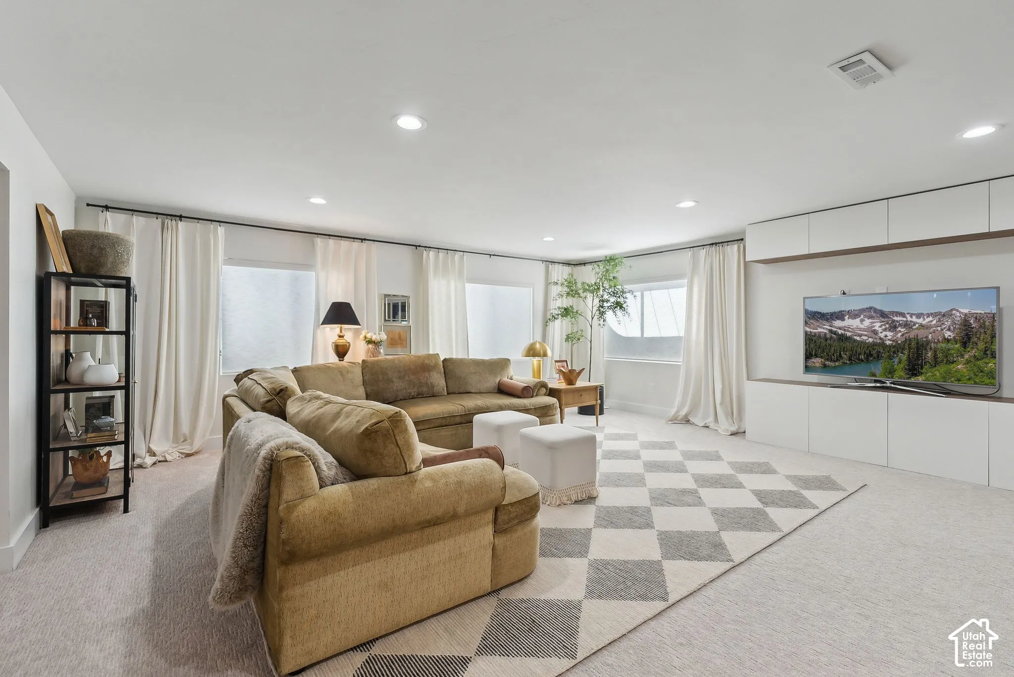 Recessed lighting, light-colored carpeting, multiple windows, and built-in white cabinetry with wood-finish accents