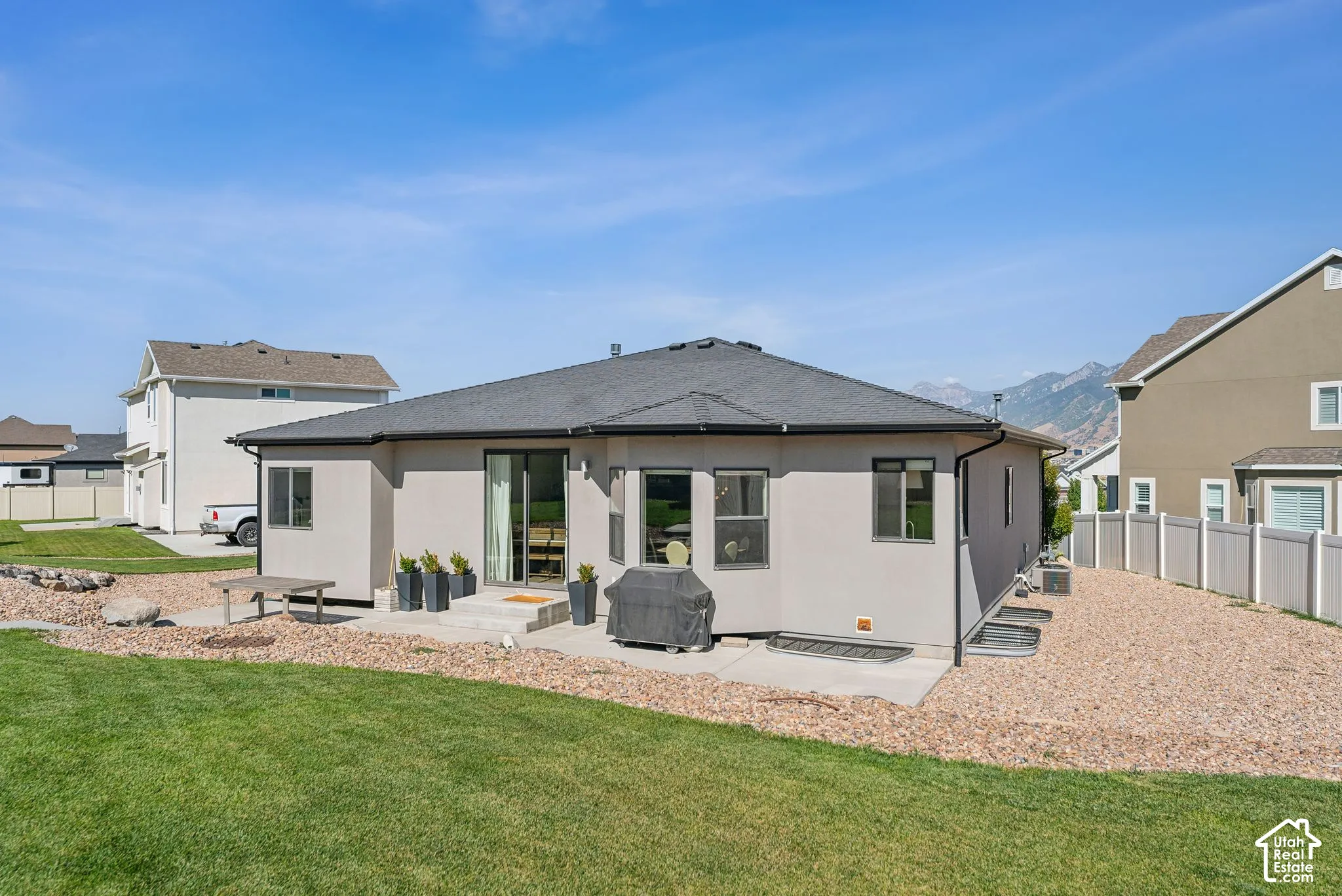 Expansive backyard featuring a manicured lawn, gravel landscaping, and a concrete patio
