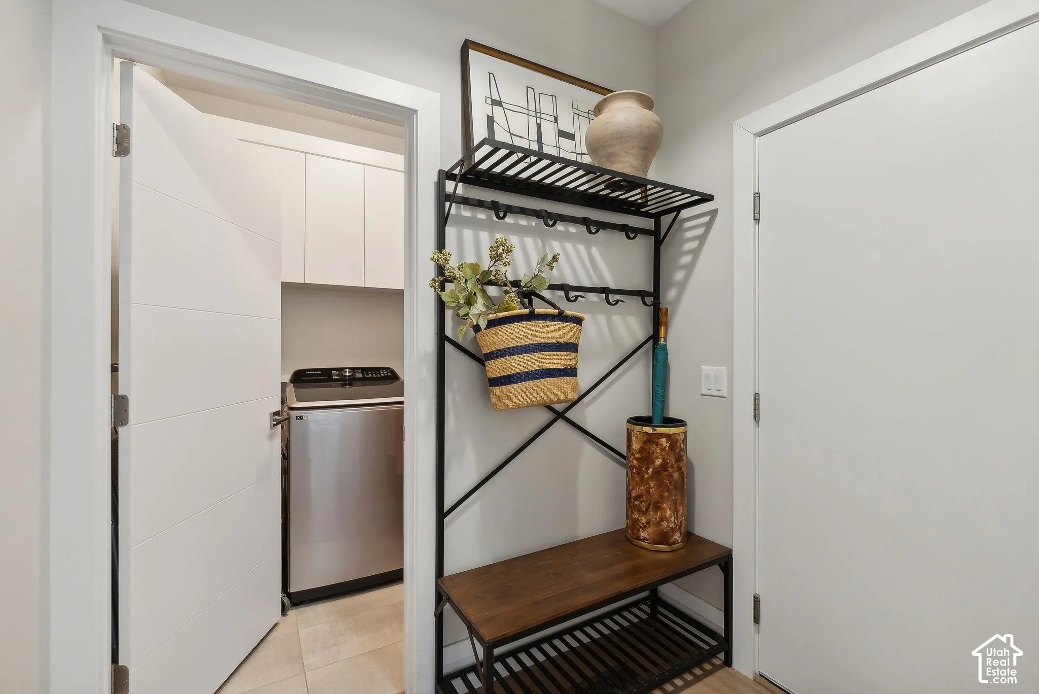 Laundry area with white cabinetry, tile flooring, and a stainless steel washing machine