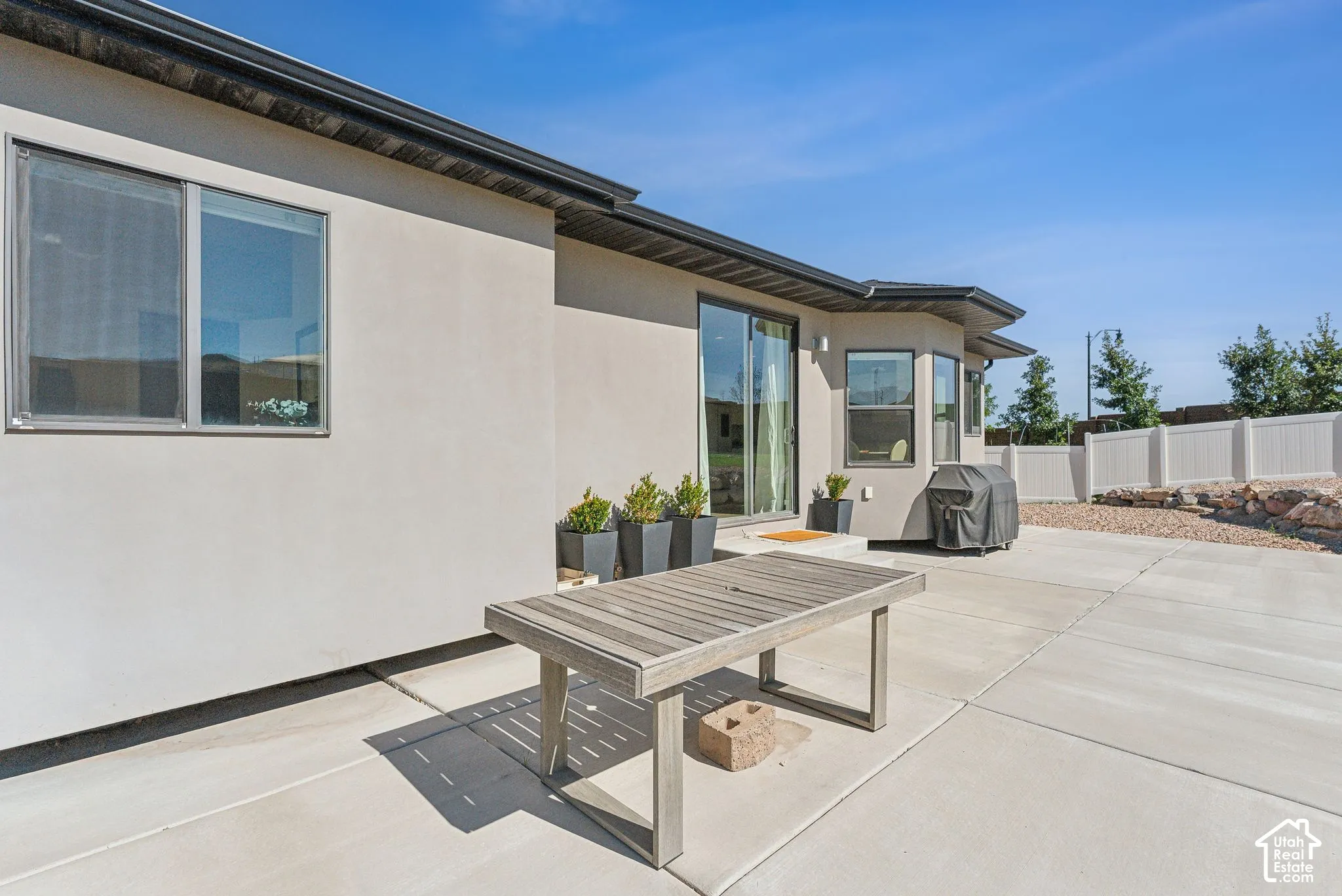 Expansive concrete patio with stucco exterior, sliding glass doors, and multiple windows