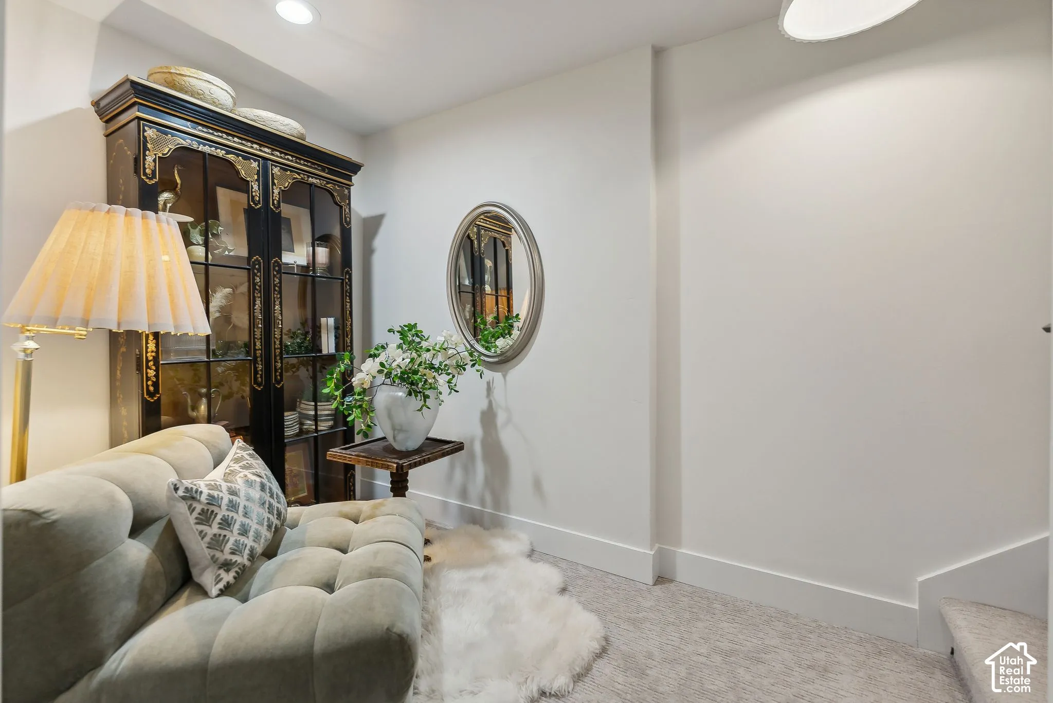 Built-in display cabinet with glass doors, recessed lighting, wall-mounted mirror, and carpeted flooring