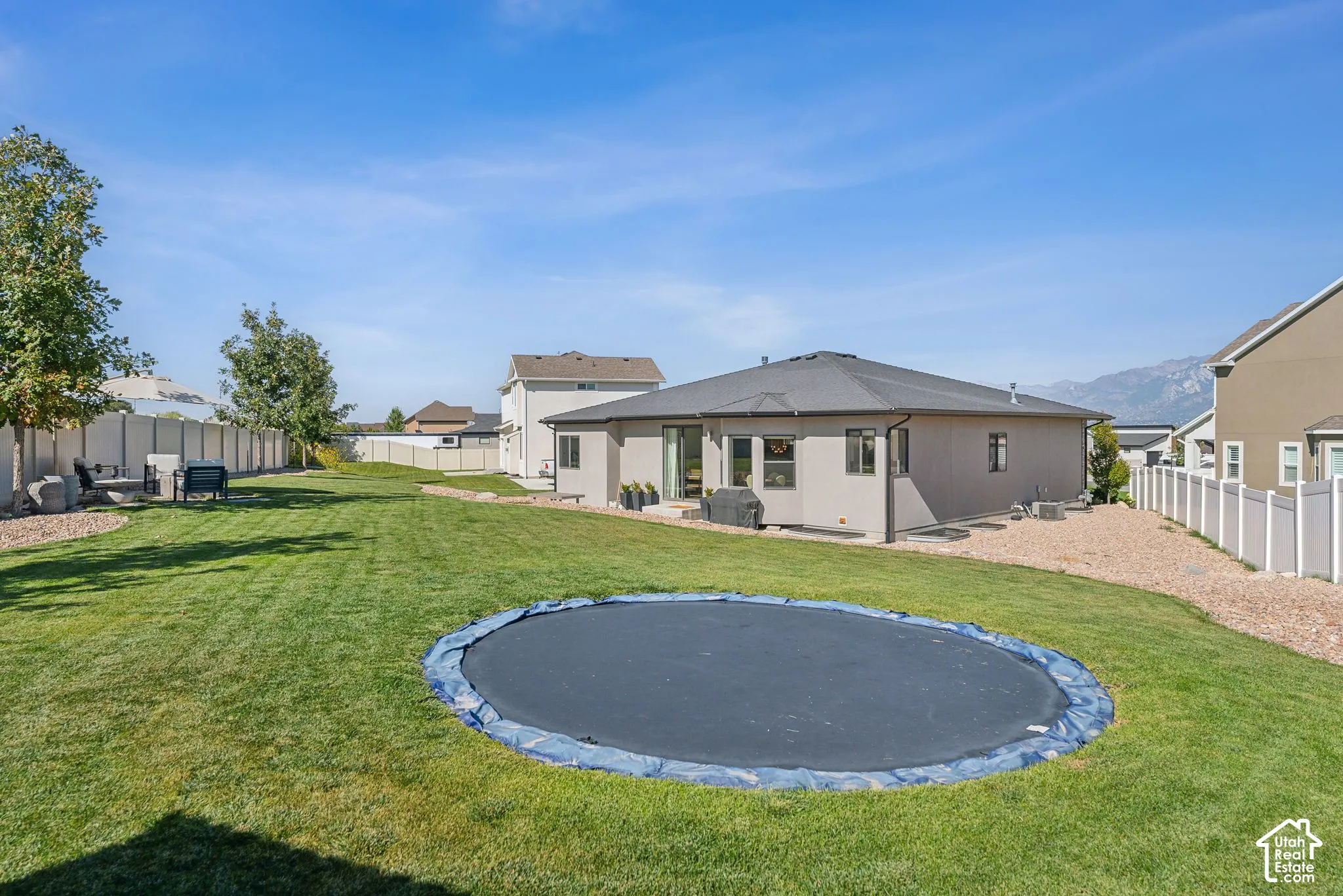Expansive backyard featuring a manicured lawn, established trees, and a concrete patio