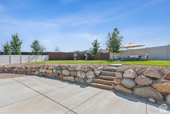 Expansive concrete patio with a stone retaining wall and integrated stone steps