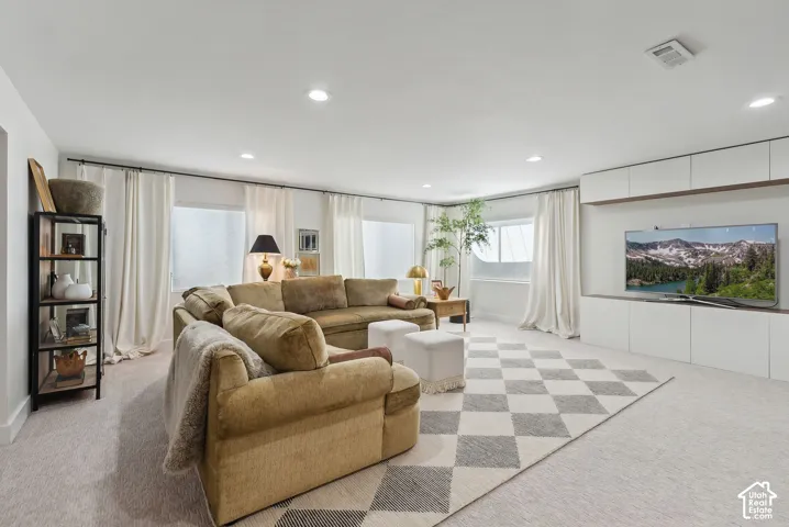 Recessed lighting, light-colored carpeting, multiple windows, and built-in white cabinetry with wood-finish accents