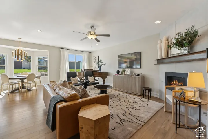 Wood-finish flooring throughout, bay windows with backyard visibility, built-in electric fireplace with mantle, recessed lighting, and ceiling fan