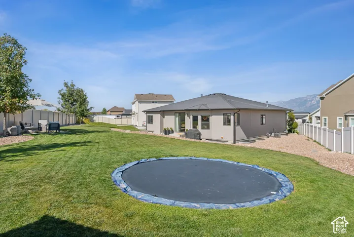 Expansive backyard featuring a manicured lawn, established trees, and a concrete patio