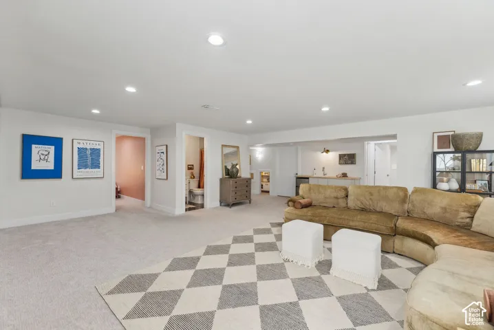 Recessed lighting, plush carpet flooring, white walls, and a built-in wet bar with a white subway tile backsplash