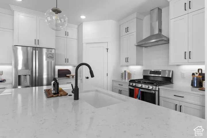 White shaker cabinetry with black hardware, stainless steel appliances, a large single basin sink with a matte black faucet, and light-toned countertops
