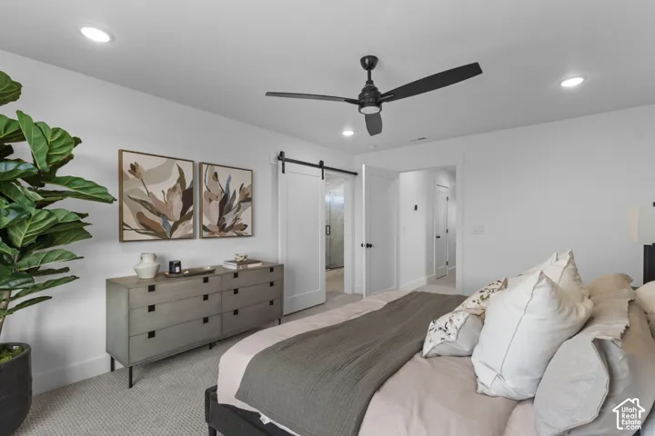 Recessed lighting, ceiling fan, white paneled doors, sliding barn door, and light-tone carpet