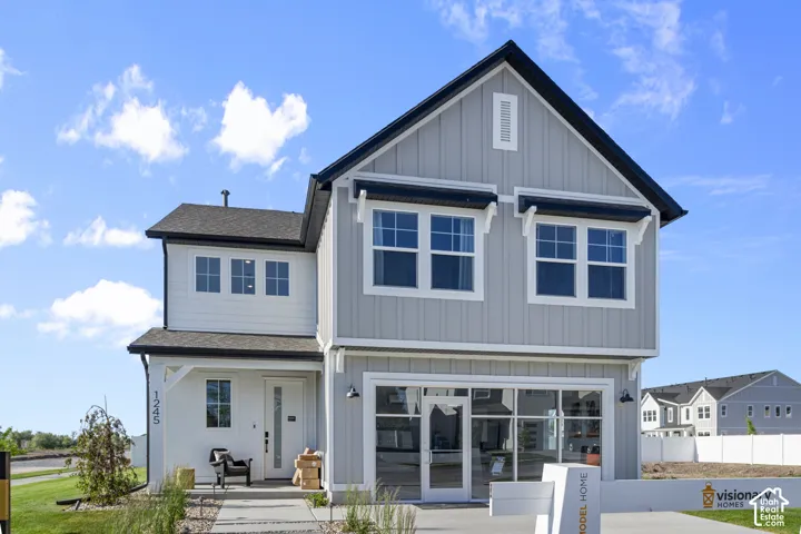Two-story exterior with a gray and white facade, prominent gable roof, and a two-car garage featuring a full-glass door