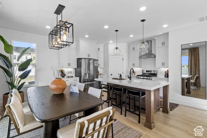 Contemporary open-concept kitchen and dining area featuring light wood-finish flooring