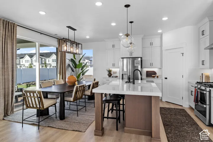 Modern kitchen featuring white cabinetry, stainless steel appliances, a center island with bar seating, and recessed lighting