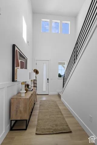 Two-story entry with wood-finish flooring, high ceilings, and tall windows