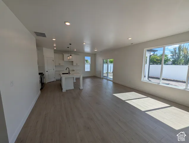 Open-concept living space with wood-finish flooring, recessed lighting, and large windows