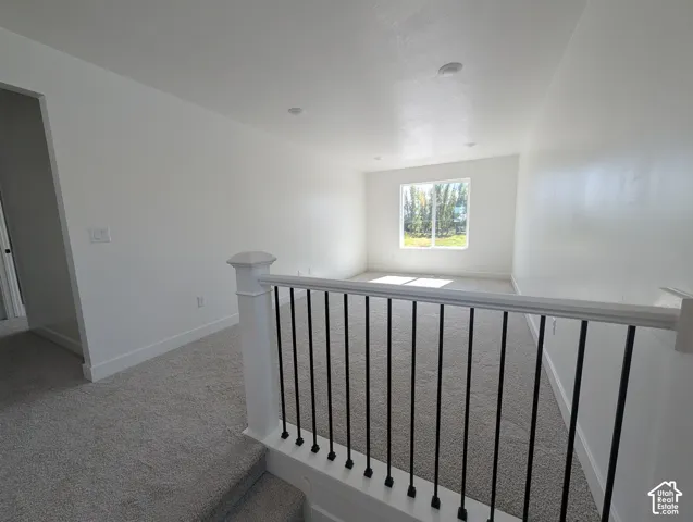 Carpeted landing with white walls, recessed lighting, and a white balustrade with black metal spindles