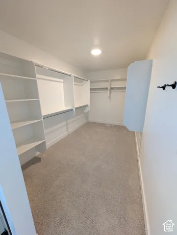 Recessed ceiling lighting, built-in shelving, hanging rods, light-colored carpet, and white walls