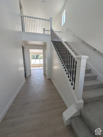 Two-story entry with wood-finish flooring, carpeted staircase, and black metal balusters