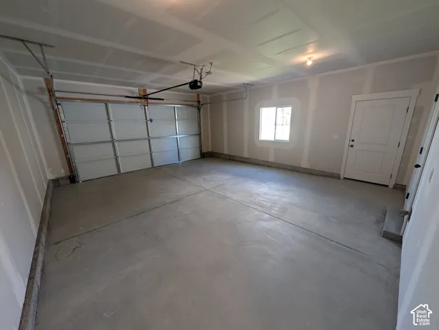 Attached garage with a concrete floor, overhead lighting, and a window
