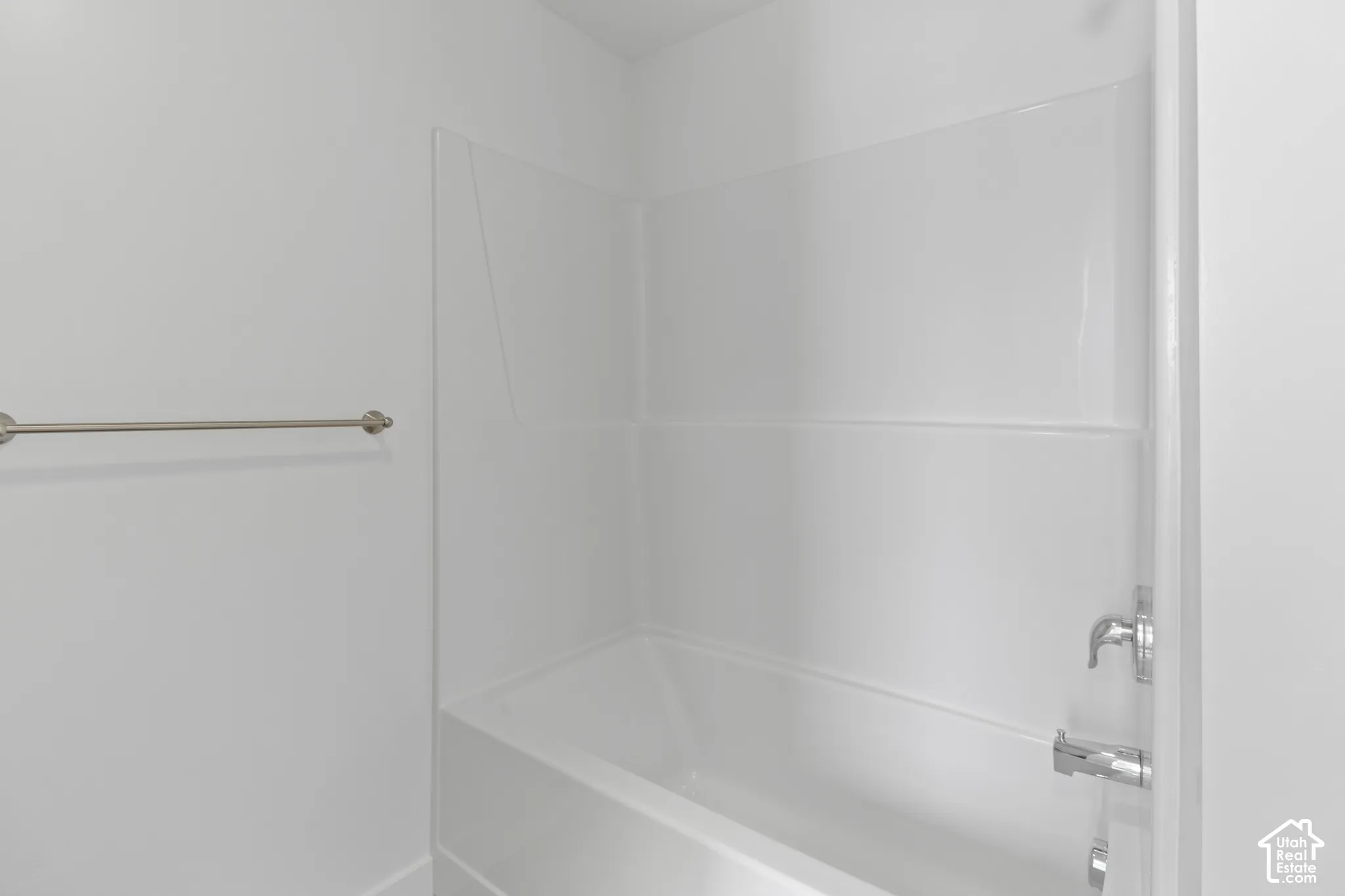 Tub and shower combination with white surround, chrome fixtures, and a brushed nickel towel bar