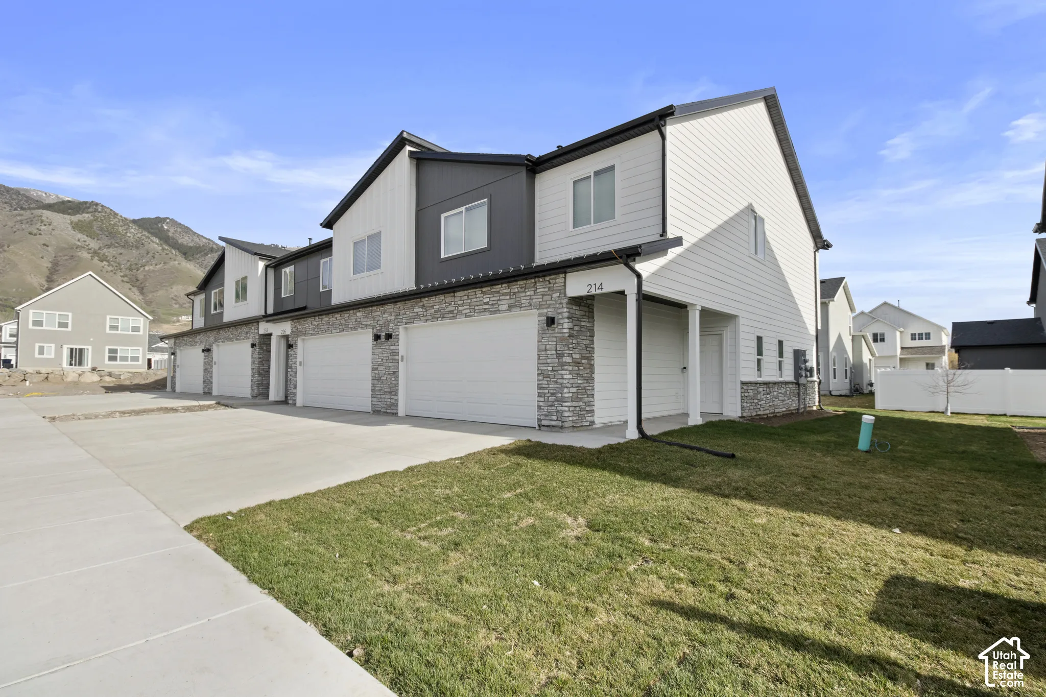 Modern townhome exterior featuring stone accents, white siding, and dark trim