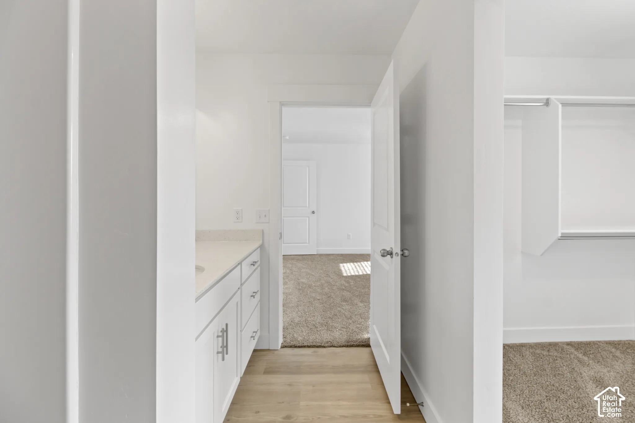 White vanity with under-mount sink, light-toned countertop, and silver-finish hardware