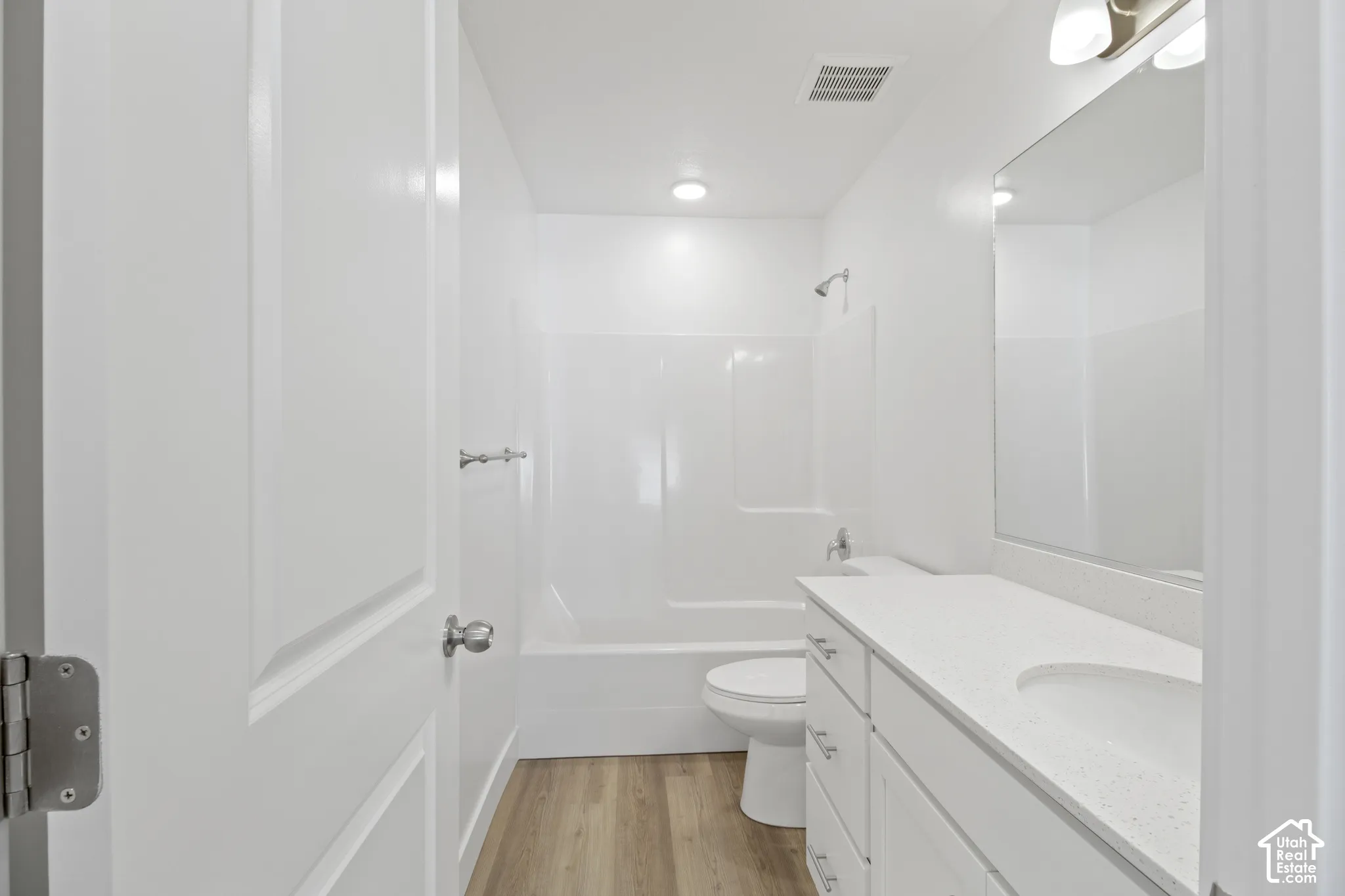 Bathroom featuring a white vanity with an integrated sink, a white countertop, and wood-finish flooring