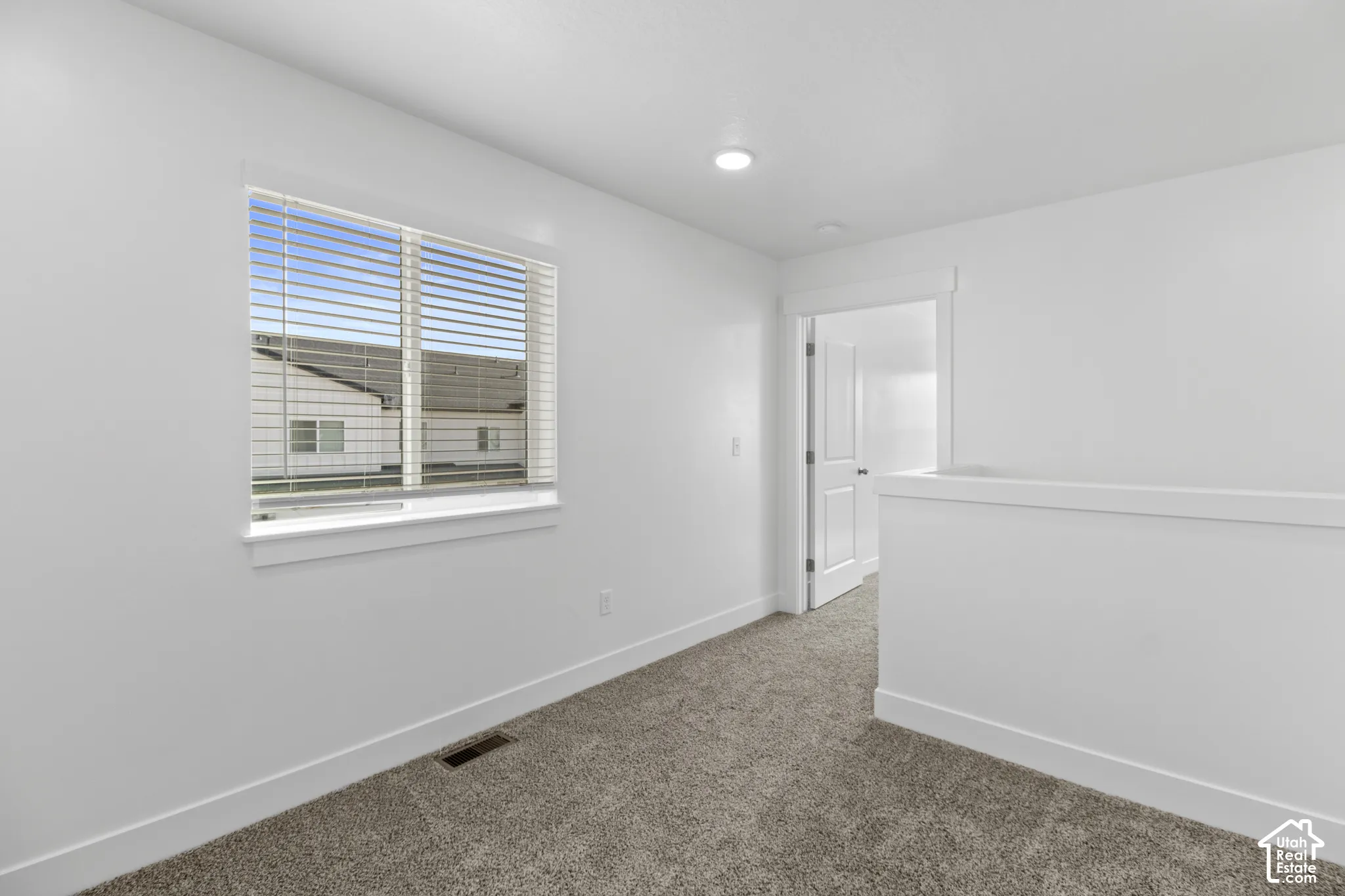 Window with blinds, white trim, recessed ceiling light, white interior door, and carpeted flooring