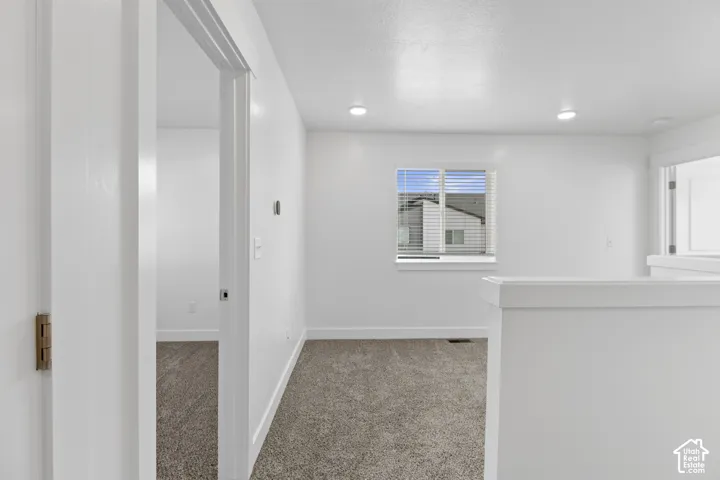 Recessed lighting, white walls, carpeted flooring, and a window with blinds