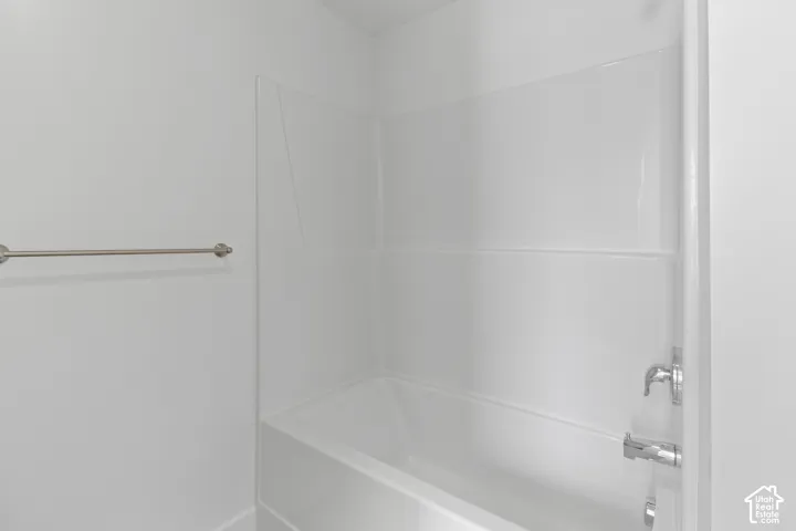 Tub and shower combination with white surround, chrome fixtures, and a brushed nickel towel bar