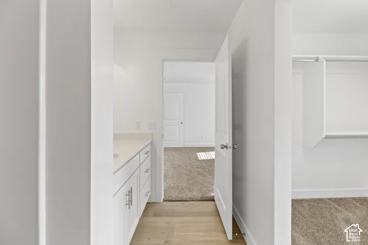 White vanity with under-mount sink, light-toned countertop, and silver-finish hardware