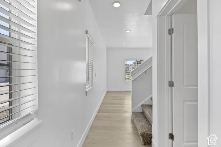 Recessed ceiling lighting, light wood-finish flooring, white horizontal blinds, and a carpeted staircase