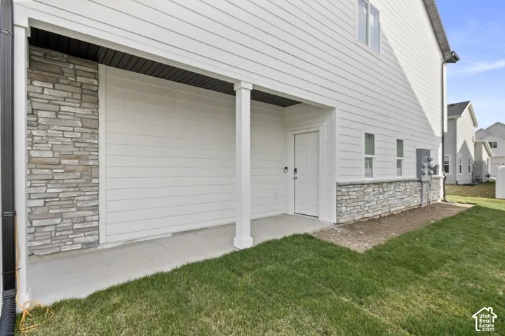 Covered entry with concrete flooring, white siding exterior, and stone veneer accents