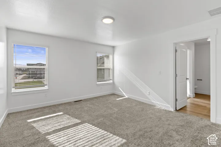 Carpeted room with white walls, two windows with blinds, and a flush mount ceiling light